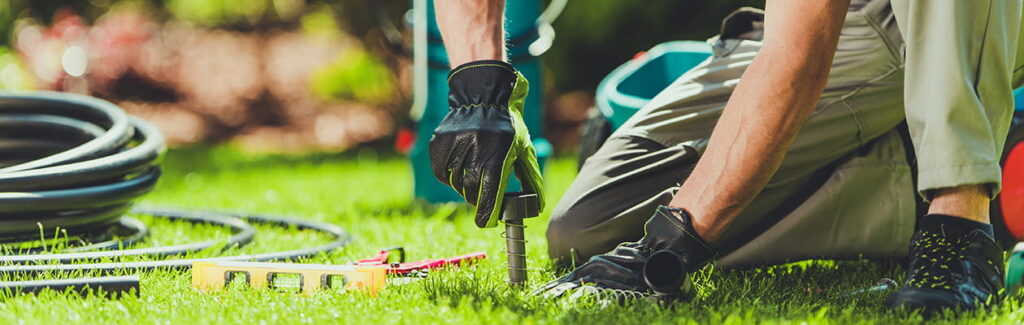 Worker Installing Irrigation System While Working on Green Lawn in Sunny Backyard During Daytime Hours
